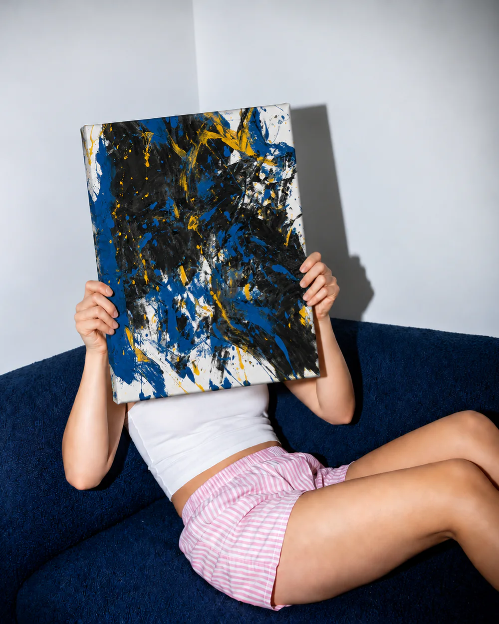 Osoba na granatowej kanapie trzyma przed twarzą niebiesko-czarny obraz na ramie 50 × 40 cm